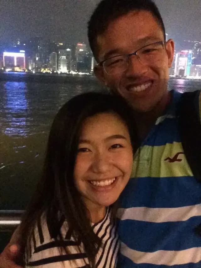 Anna and John smiling together beside Victoria Harbour at night